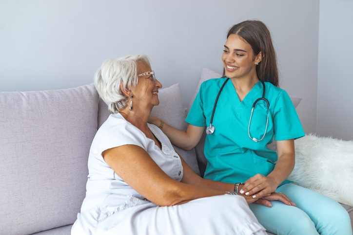 A woman sits at a sofa while a female doctor discusses respite care services in Shreveport, LA
